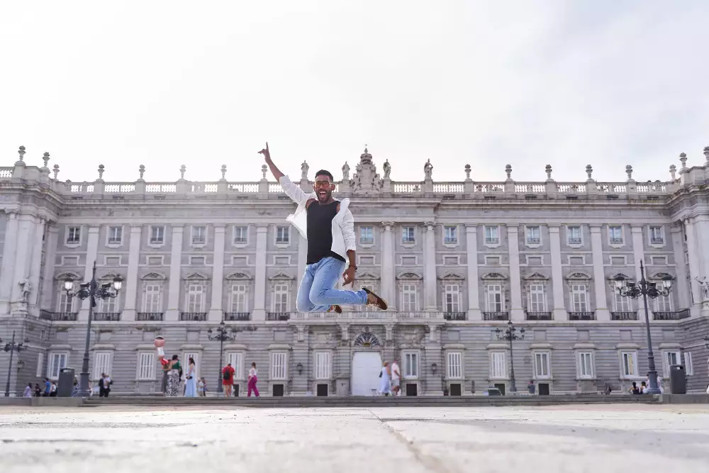 estudiante universitario saltando frente al Palacio Real de Madrid